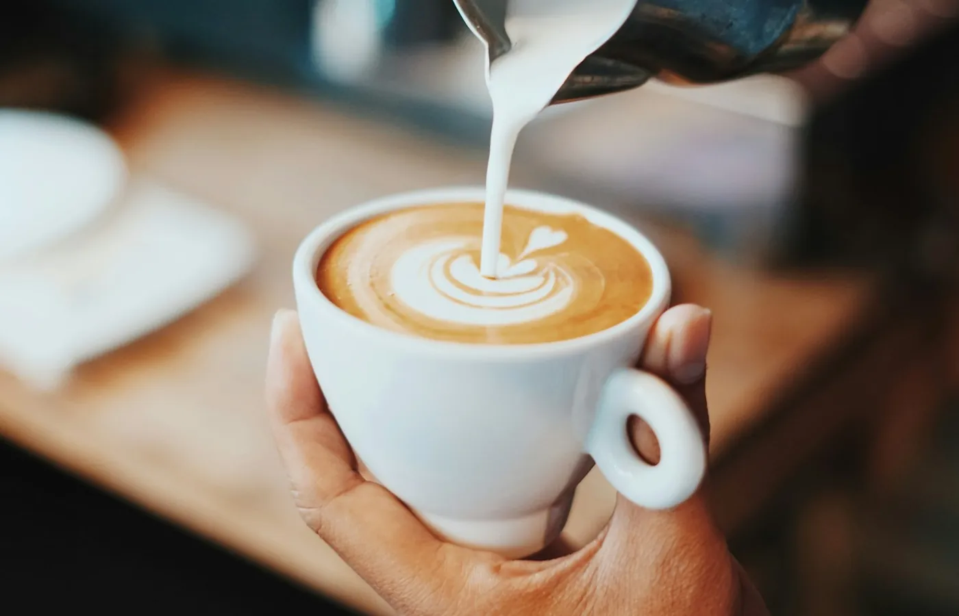 Barista nalévá mléko do latté